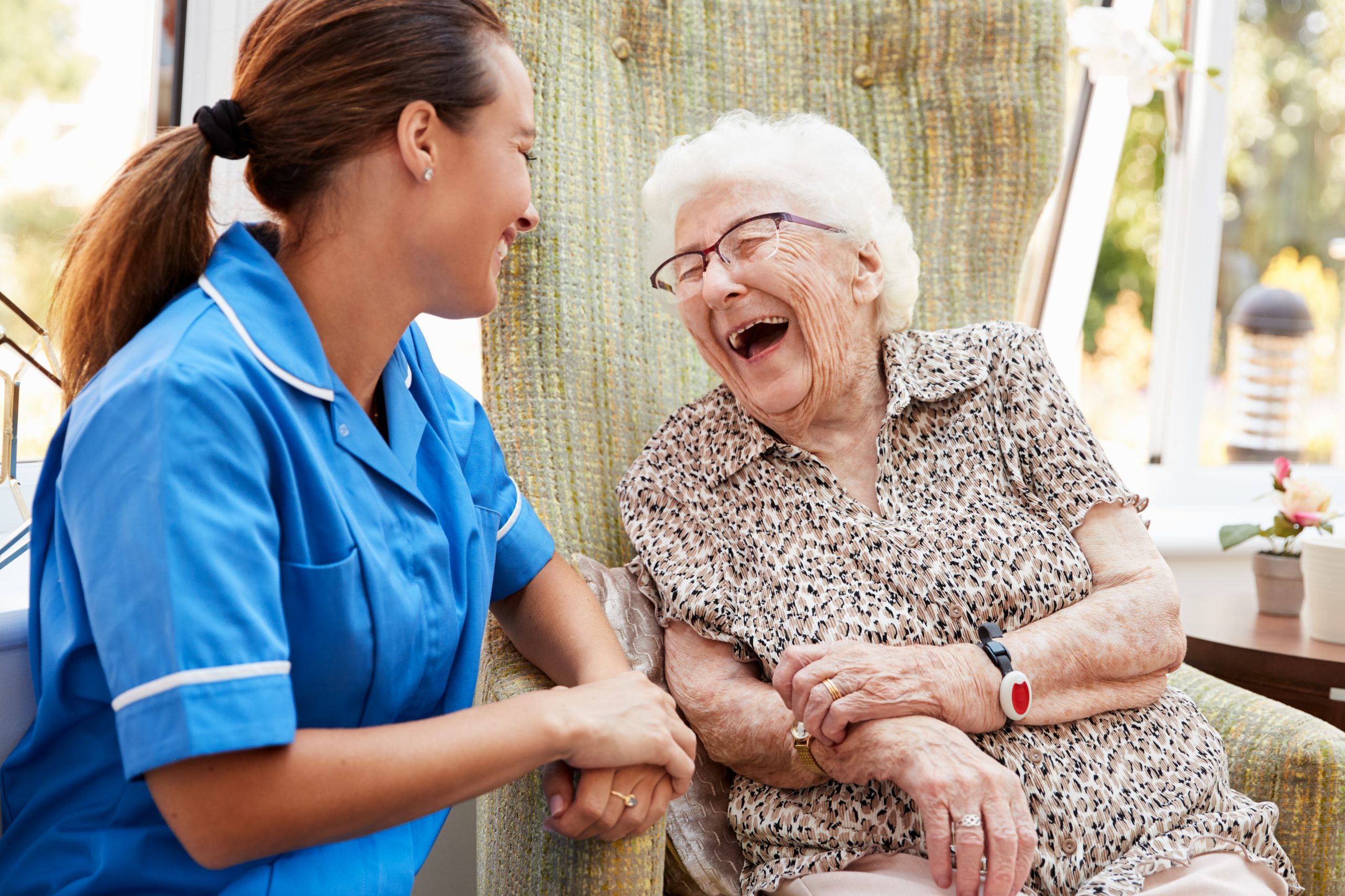 Senior woman and a caregiver having cheerful conversation in a care home